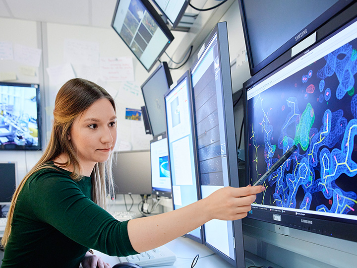 Woman pointing to protein structure on monitor