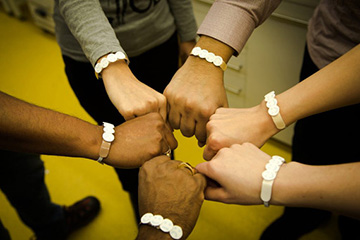 six arms of different skin tones, each wearing UV wristband